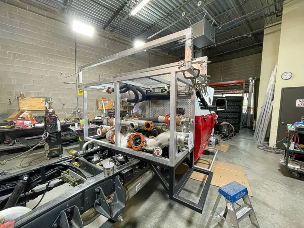 Exterior view of small fire truck showing cab, body compartments, and wheel/tire area.